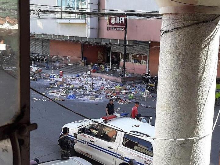 Polizisten untersuchen das Gelände vor einem Einkaufszentrum nach der Bombenexplosion.