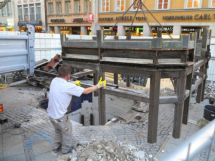 Mit dem Kran heben die Bauarbeiter den alten Aufzug zwischen Sperrengeschoss und Oberfläche am Marienplatz aus den Fugen.