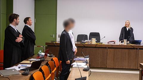 Zwei angeklagte Männer (M) stehen zu Prozessbeginn mit ihren Anwälten (l) auf der Anklagebank.