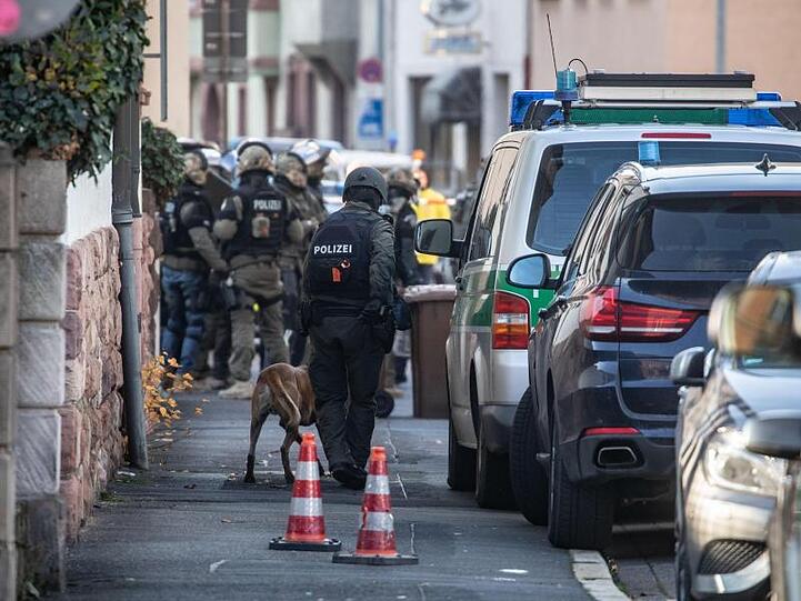 Polizisten stehen am Rand eines Gebäudes, in dem sich ein bewaffneter Mann verschanzt hat.