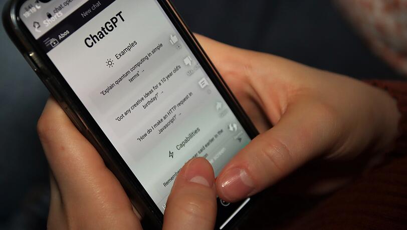 Eine Person gibt am Handy etwas in das Programm ChatGPT ein.
