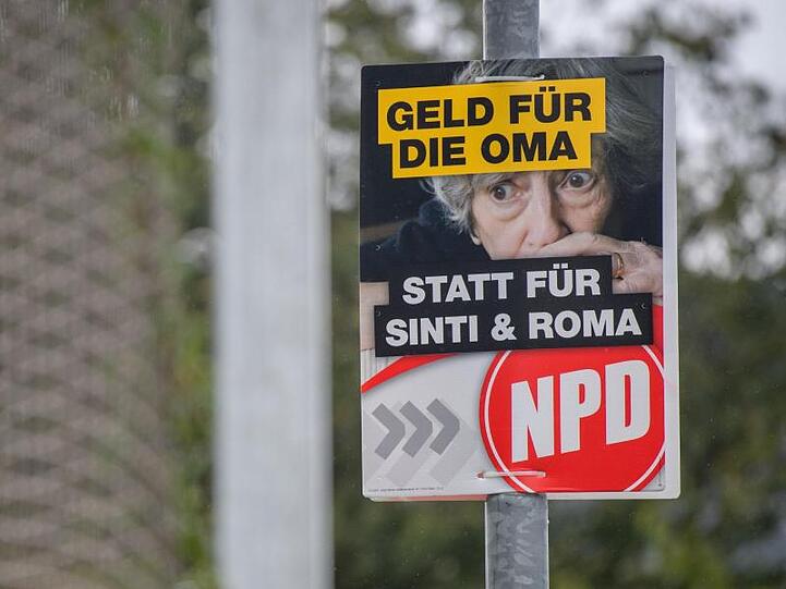 Ein Wahlplakat der NPD mit der Aufschrift "Geld für die Oma statt für Sinti und Roma" hängt am Straßenrand. Foto: Matthias Balk/Archivbild