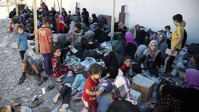 Frauen und Kinder sitzen im Irak an einem Sammelpunkt für vertriebene Menschen.