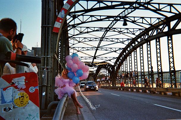 Der Obdachlose Johan fotografierte diese Szene an der Hackerbrücke. Gerade posiert dort das Model Melinda (Instagram: melinda.prade) in einem märchenhaften Kleid mit Ballons für ein Shooting. Dieser Moment vor der prunkvollen Brückenkonstruktion habe ihn sehr berührt, sagt er.