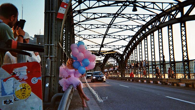 Der Obdachlose Johan fotografierte diese Szene an der Hackerbrücke. Gerade posiert dort das Model Melinda (Instagram: melinda.prade) in einem märchenhaften Kleid mit Ballons für ein Shooting. Dieser Moment vor der prunkvollen Brückenkonstruktion habe ihn sehr berührt, sagt er.