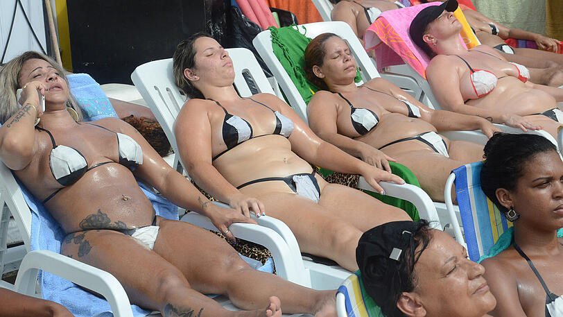Frauen sonnen sich auf einer Dachterrasse in Rio de Janeiro. Sie tragen Bikinis aus Klebestreifen, dies soll besonders weiße Bräunungsstreifen fördern.