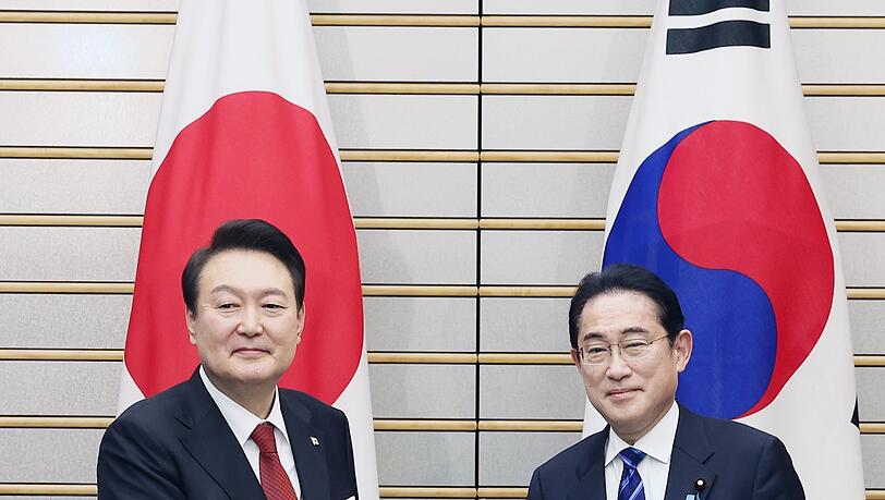 Südkoreas Präsident Yoon Suk Yeol (l.) und Japans Premier Fumio Kishida reichen sich vor ihren Gesprächen die Hände.