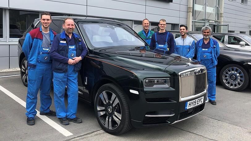 Daniel (v.l.) und Andi mit weiteren Werksmitarbeitern in Unterhollerau neben einem Cullinan. Sie fertigen die Karosserien sämtlicher Rolls-Royce-Modelle.