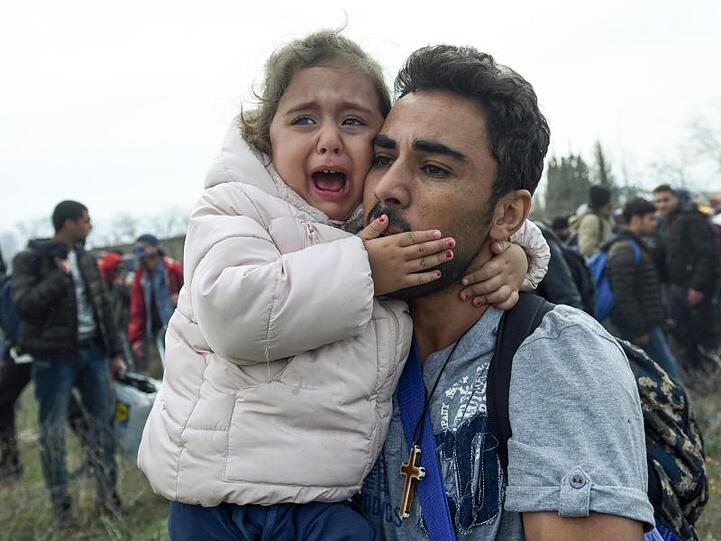 Ein Mann hält ein weinendes Mädchen. Die Hoffnung zahlreicher Migranten nach Mitteleuropa zu gelangen, schwindet nicht.