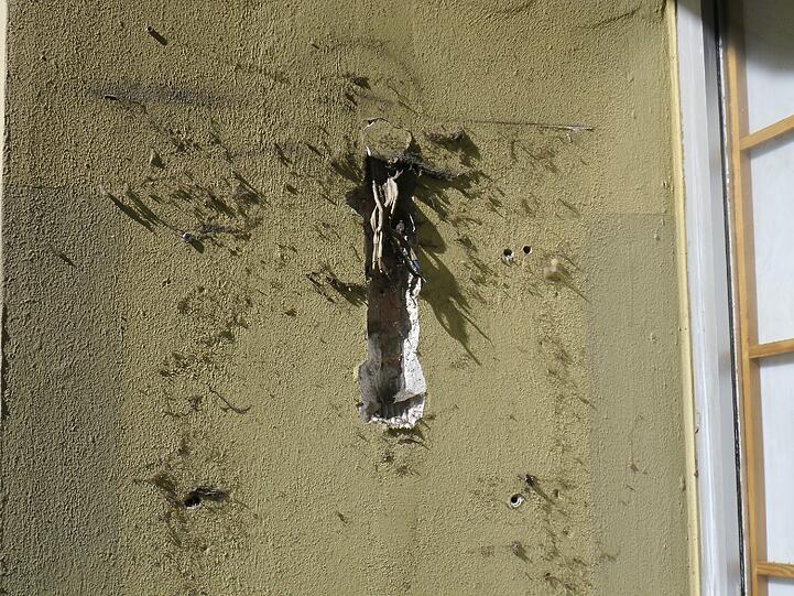 Neben dem Eingang hängen elektrische Kabel aus der Wand.
