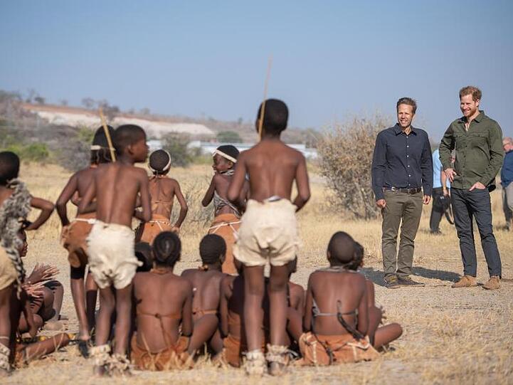 Prinz Harry und Mike Chase, Gründer von Elephants Without Borders, werden von Schulkindern im Chobe-Nationalpark begrüßt.