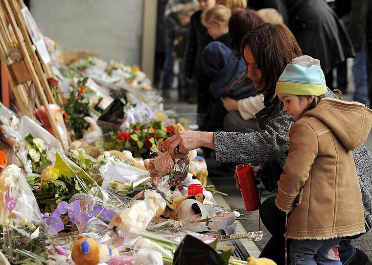Eine Familie legt Blumen vor der Kinderkrippe "Fabeltjesland" ab.