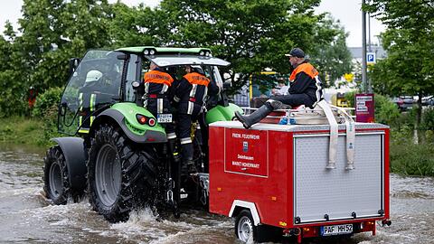 Feuerwehrleute fahren in Reichertshofen über eine überflutete Straße.