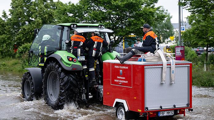 Feuerwehrleute fahren in Reichertshofen über eine überflutete Straße.