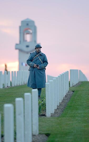 Ein Mann, der wir ein französischer Soldat aus dem ersten weltkrieg verkleidet ist schreitet während eines Morgengottesdienstes in Villers-Bretonneux an australischen Kriegerdenkmälern vorbei.