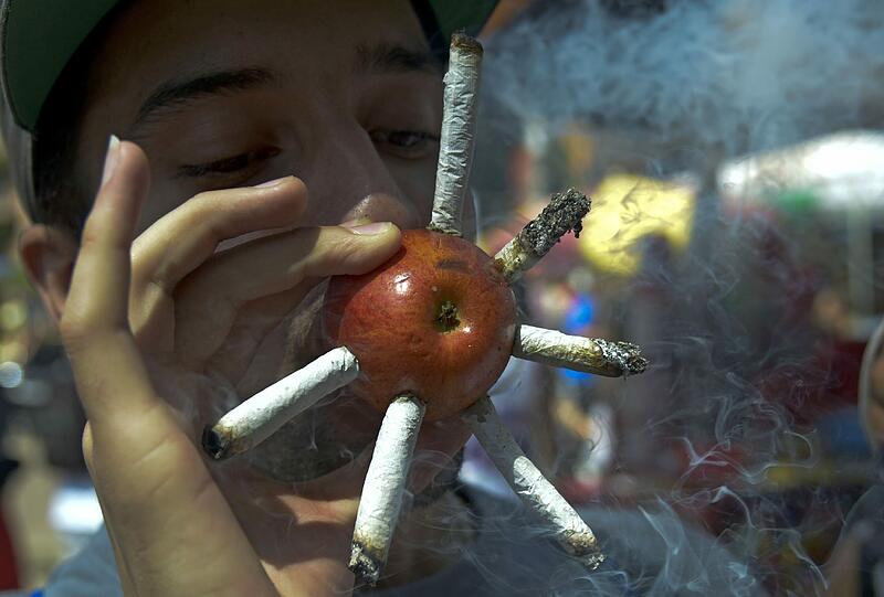 Ein junger Mann zieht ein paar Joints durch und zwar durch einen Apfel! Fotografiert auf einer Demo zu Legalisierung von Marihuana in Kolumbien.