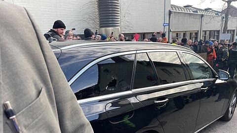 Ein Auto mit eingeschlagener Scheibe vor der Veranstaltungshalle.