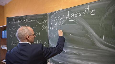 Peter Cypra, Richter am Amtsgericht Tempelhof-Kreuzberg, schreibt in einer Willkommensklasse in der Albert-Gutzmann-Grundschule den ersten Artikel des Grundgesetzes an die Tafel.