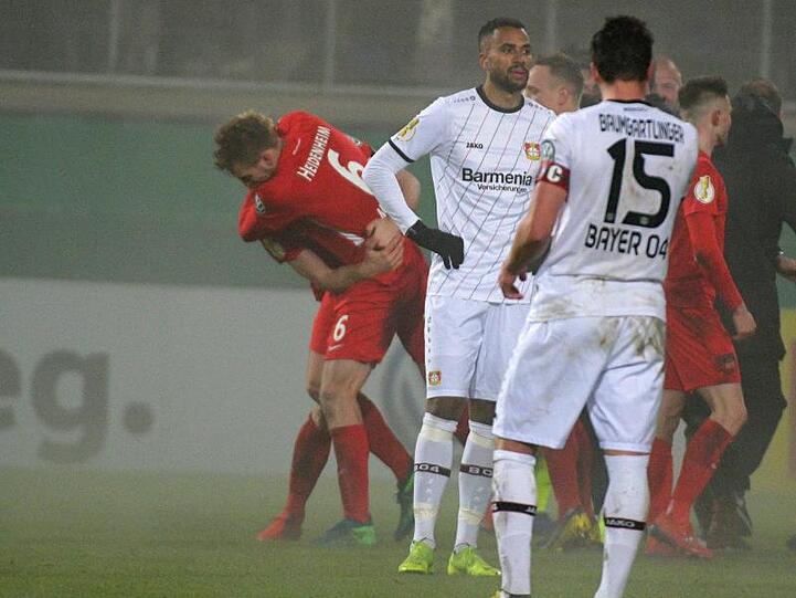 Während die Heidenheimer im Hintergrund ihren Sieg feiern, lassen die Spieler von Bayer Leverkusen nach dem Aus im Pokal-Achtelfinale die Köpfe hängen.