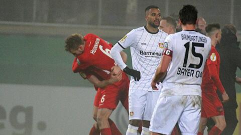 Während die Heidenheimer im Hintergrund ihren Sieg feiern, lassen die Spieler von Bayer Leverkusen nach dem Aus im Pokal-Achtelfinale die Köpfe hängen.