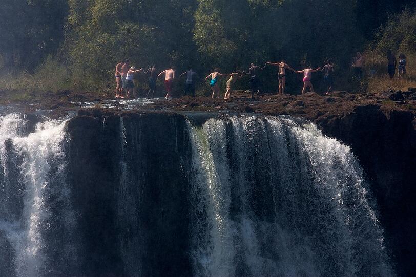 Der Devil's Pool an den Victoriaf&auml;llen ist nichts f&uuml;r schwache Nerven: Ein nat&uuml;rlicher Felspool, der direkt am Rand des tosenden Wasserfalls liegt. In der Trockenzeit, wenn der Wasserstand niedrig ist, kann man hier baden und ist dabei nur durch eine schmale Felskante vom &uuml;ber hundert Meter tiefen Abgrund getrennt. Der Ort gilt als ultimativer Infinity-Pool und zieht Adrenalinjunkies aus aller Welt an.