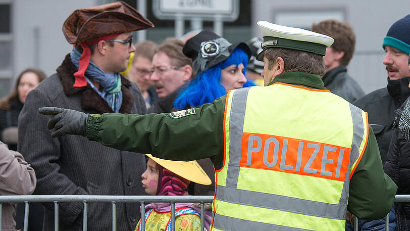 Ein Polizist spricht während des traditionellen Chinesenfaschingsumzugs in Dietfurt mit Zuschauern.