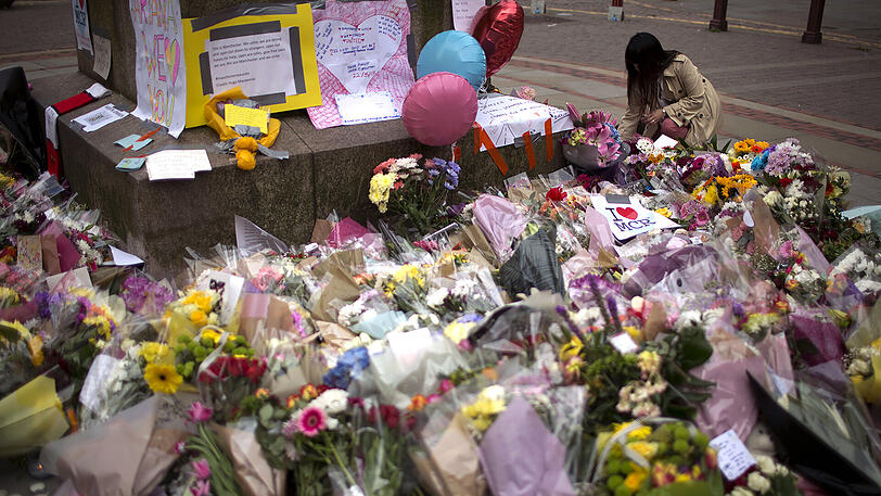 Eine Frau legt einen Blumenstrauß für die Opfer des Terroranschlags in Manchester nieder. Nach dem verheerenden Anschlag auf ein Popkonzert der Sängerin Ariana Grande in der Manchester Arena mit mindestens 22 Todesopfern hat Großbritannien die Terrorwarnstufe auf das höchste Niveau angehoben.