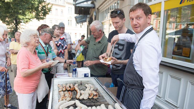 Für den Wahlkampf stellt sich Sachsens Ministerpräsident Michael Kretschmer (CDU, r.) auch mal an den Grill.