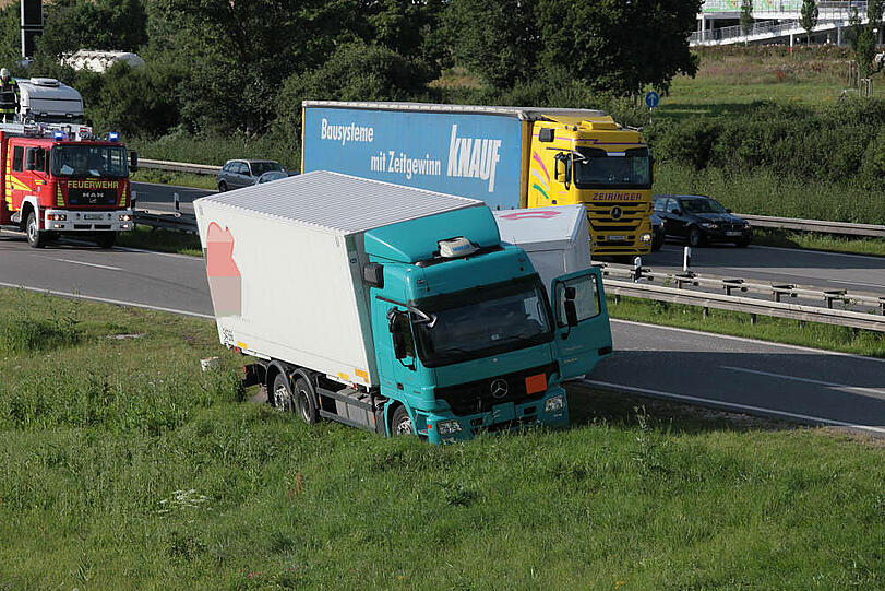 Vermutlich weil er zu schnell auf die Autobahn fährt, kommt ein Laster in der Kurve von der Fahrbahn ab und fährt in die Leitplanke. Sein Hänger kippt um.