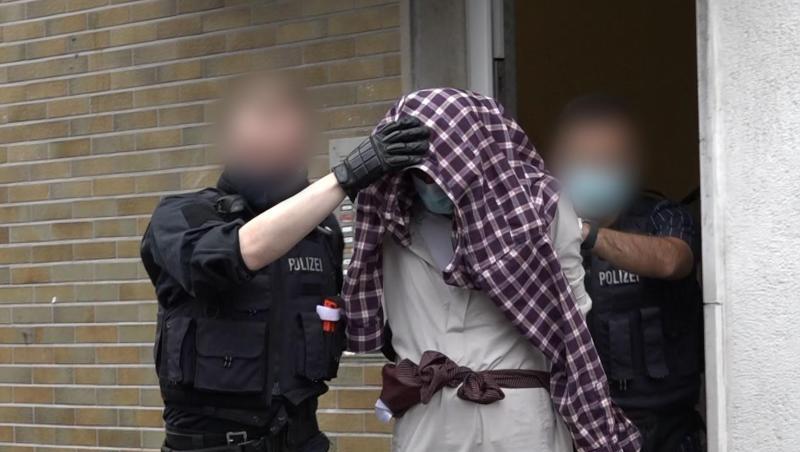 Ein Mann wird im Zusammenhang mit dem mutmaßlich geplanten Anschlag von Polizisten abgeführt.