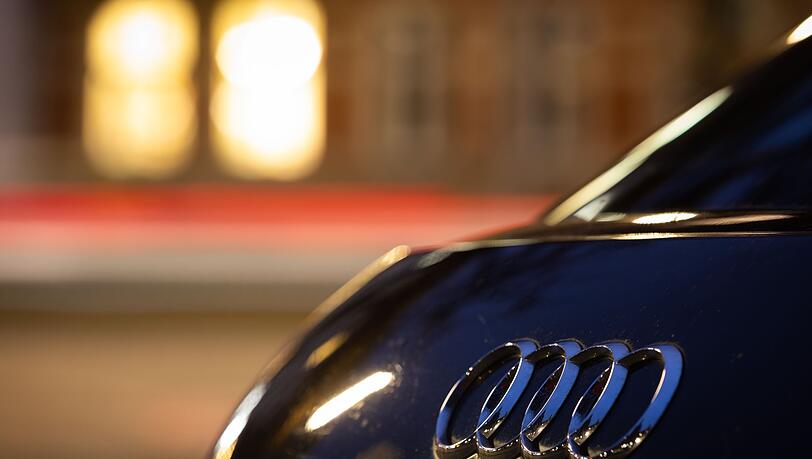 Das Logo vom Automobilhersteller Audi ist am Abend an einem Fahrzeug zu sehen.
