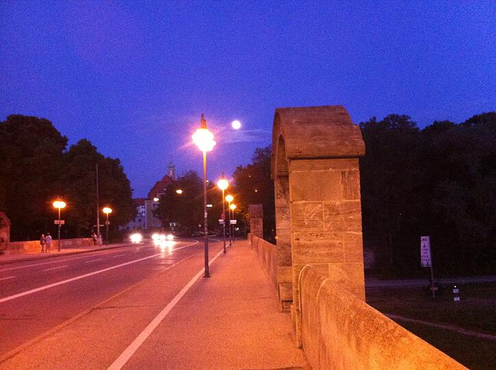 Vorne das Laternenlicht auf der Wittelsbacherbrücke, dahinter leuchtet der Mond.