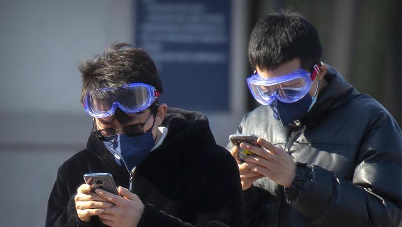 Reisende tragen Mundschutz und Schutzbrillen, während sie auf ihre Smartphones schauen. Foto: Mark Schiefelbein/AP/dpa/Archiv Reisende tragen Mundschutz und Schutzbrillen, während sie auf ihre Smartphones schauen. Foto: Mark Schiefelbein/AP/dpa/Archiv