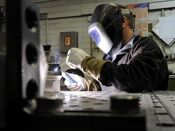 Ein Mitarbeiter eines metallverarbeitenden Betriebs schweißt an einem Werkstück. Foto: Carsten Rehder/dpa/Archivbild