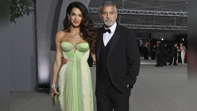 Amal Clooney in einem grünen Designerkleid und George Clooney im eleganten Dreiteiler.