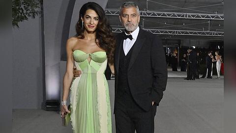 Amal Clooney in einem grünen Designerkleid und George Clooney im eleganten Dreiteiler.