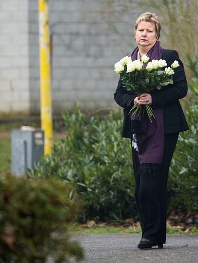 Schulministerin Sylvia Löhrmann trägt einen Blumenstrauß an die Schule.