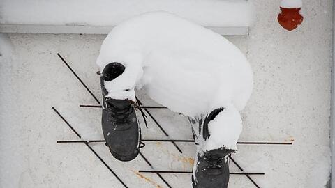 Schuhe hängen an einer verschneiten Hausmauer. Foto: Erwin Scheriau