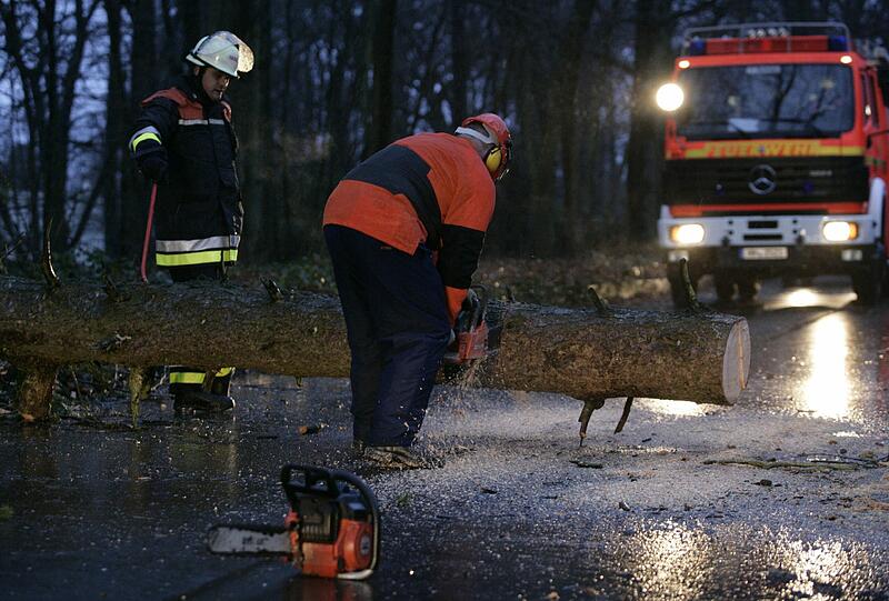 Ein Feuerwehrmann zersägt am Donnerstag (05.01.2012) in Hamburg einen auf die Straße gestürzten Baum. Sturmtief «Andrea» sorgt für reichlich Sturm und Regen im Norden.