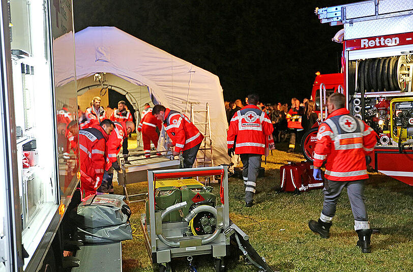 Rettungskräfte stehen in Naila vor einem der Behandlungszelte, in denen die Verletzten versorgt werden.