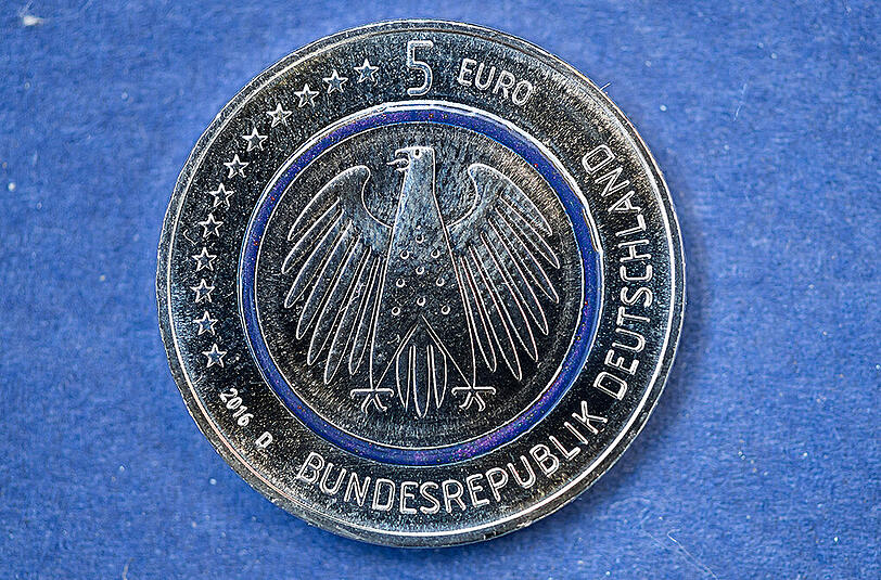 Die neue deutsche Fünf-Euro-Münze hat in der Mitte einen durchsichtigen, blau schimmernden Ring aus Kunststoff. Foto: Sven Hoppe