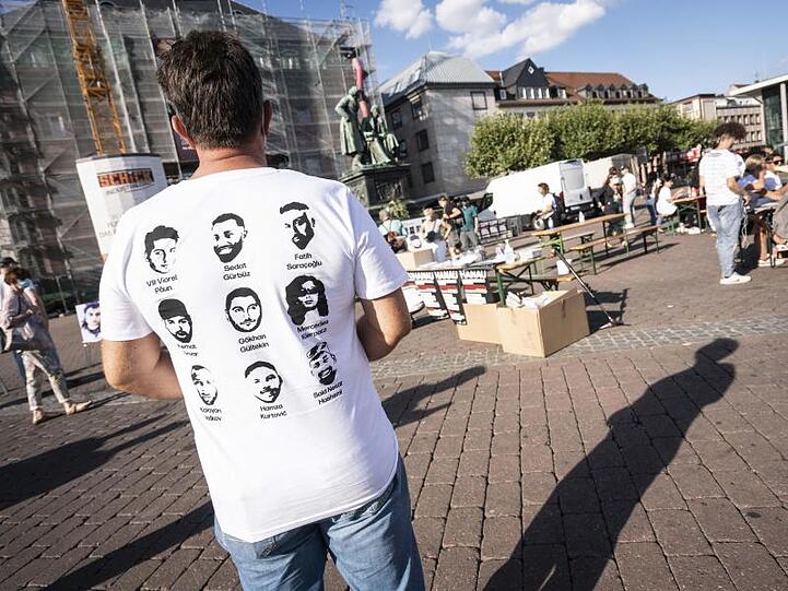 Ein Mann trägt ein T-Shirt mit den Gesichtern der Opfer des Anschlags.