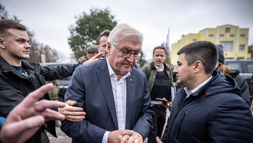 Bundespräsident Frank-Walter Steinmeier (Mitte) spricht mit Ratan Achmedow, Bürgermeister der Stadt Korjukiwka - in diesem Moment ertönt Luftalarm, und Sicherheitskräfte weisen den Weg in den Luftschutzbunker.