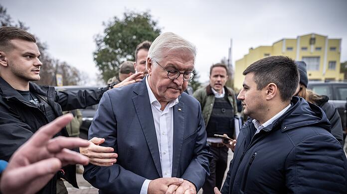 Bundespräsident Frank-Walter Steinmeier (Mitte) spricht mit Ratan Achmedow, Bürgermeister der Stadt Korjukiwka - in diesem Moment ertönt Luftalarm, und Sicherheitskräfte weisen den Weg in den Luftschutzbunker.
