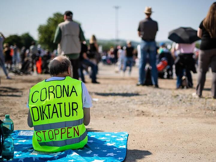 Ein Teilnehmer trägt auf dem Cannstatter Wasen in Stuttgart eine Warnweste mit der Aufschrift "Corona Diktatur stoppen".