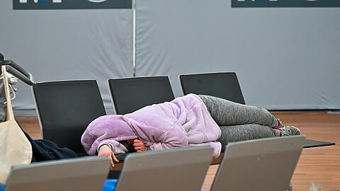 Verdi-Streik am Flughafen München: Eine Frau schläft in den Morgenstunden am Terminal 2 auf einer Bank im Abfertigungsbereich.