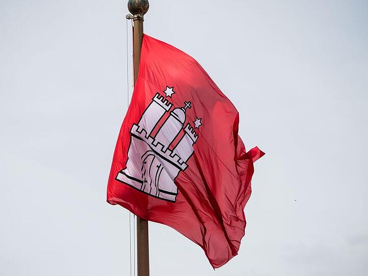 Die Fahne mit dem Wappen Hamburgs vor dem Rathaus der Hansestadt.