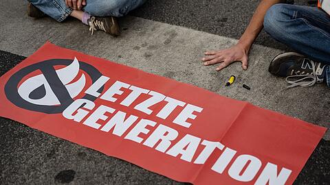 Ein Aktivist der Gruppe "Letzte Generation", der seine Hand selbst auf der Straße festgeklebt hat, blockiert eine Kreuzung in Göttingen.