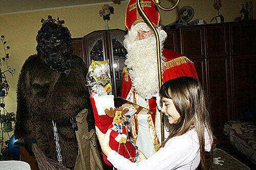 Besuch bei Familie Müller in Ramersdorf: Der Nikolaus lobt und verteilt Geschenke, im Hintergrund lauert der Krampus.