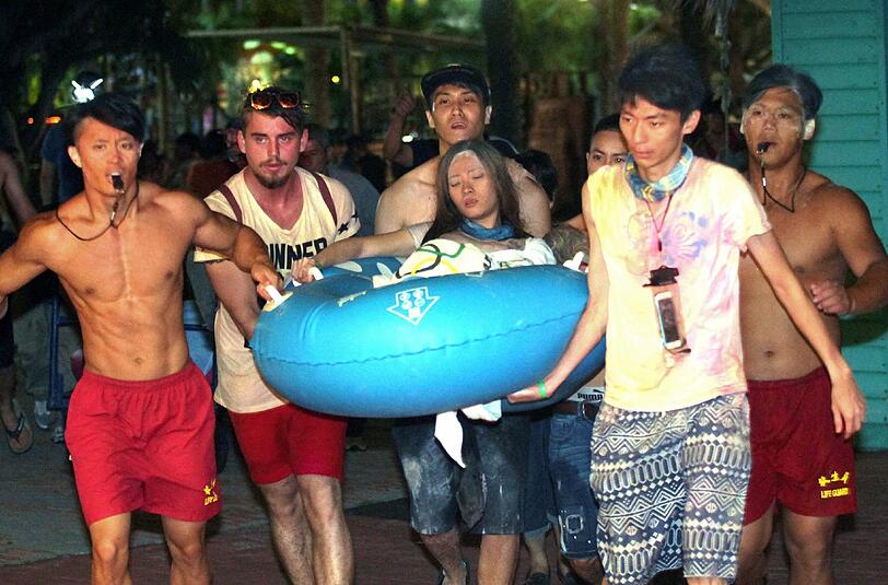 Ein riesiger Feuerball fegte über Besucher des "Formosa Water Park" in Taiwan hinweg. Helfer bringen eine junge Frau zu einem Krankenwagen.